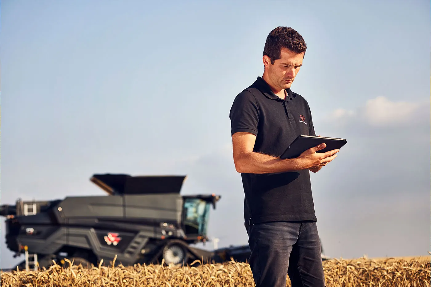 Agricoltore con tablet davanti a una mietitrebbia Massey Ferguson
